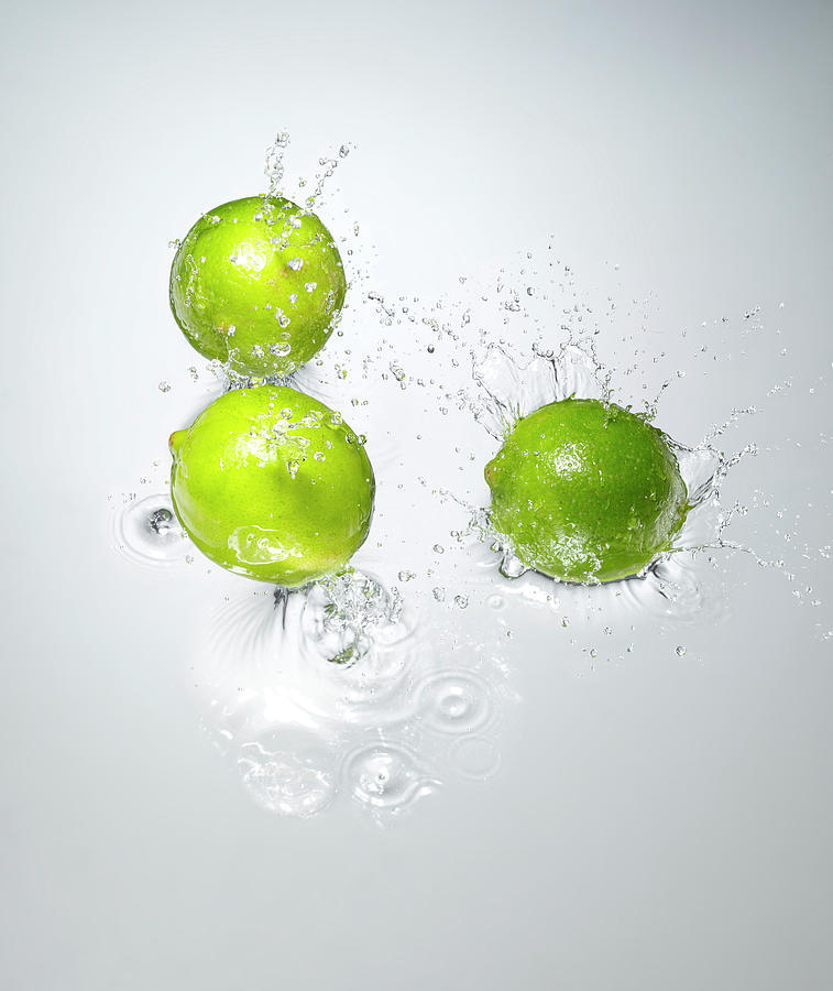Limes Splashing In To Water Photograph by Chris Stein