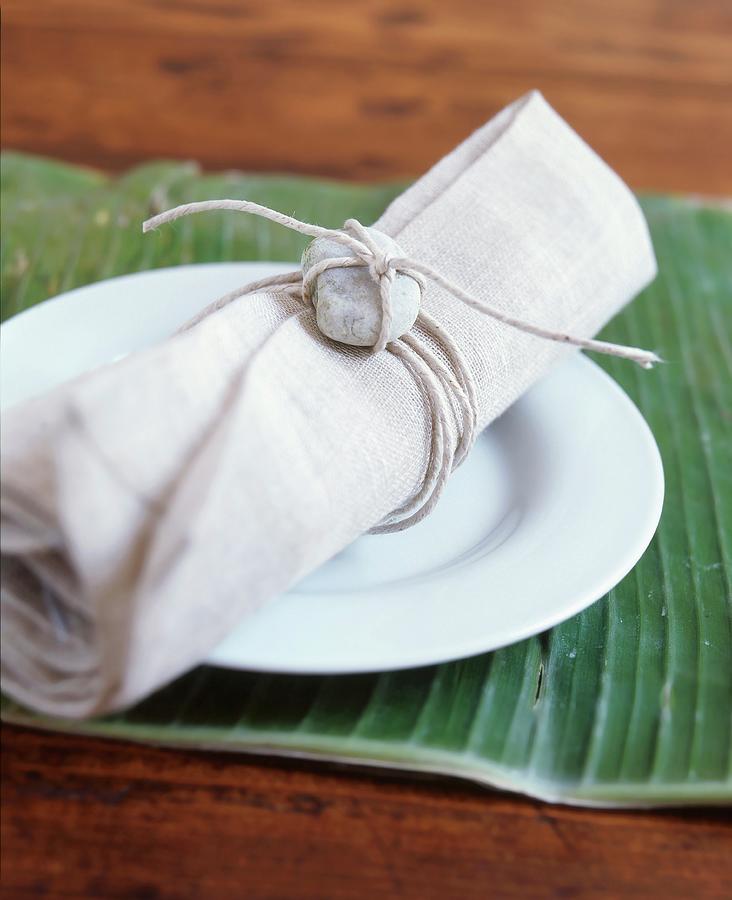 Linen Napkin Decorated With Pebble On White Plate On Banana Leaf Used As Place Mat Photograph by Veronika Stark