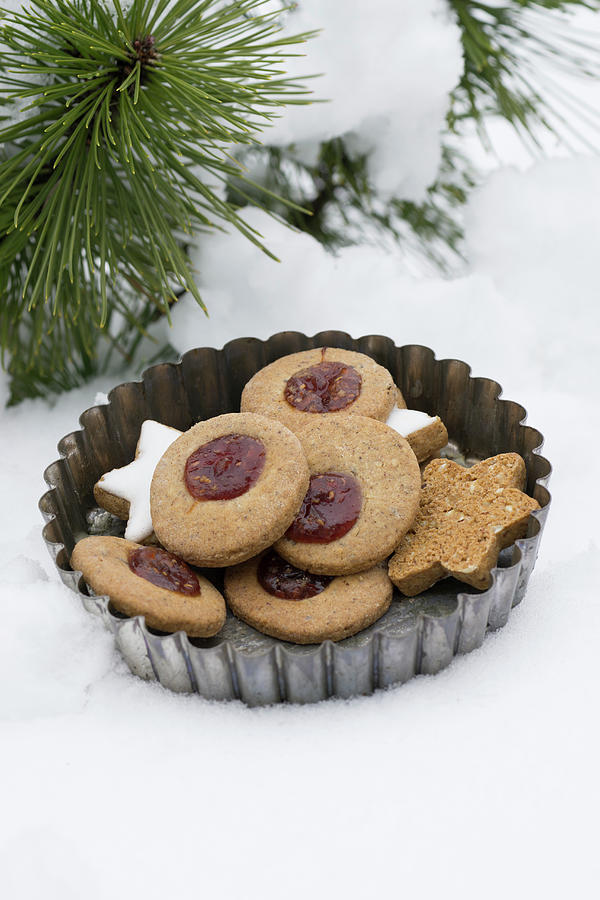 Linzer Pltzchen nutty Shortcrust Biscuits Topped With Jam And Cinnamon Stars In A Vintage Tart Tin In The Snow Photograph by Martina Schindler