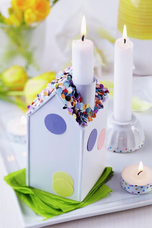 Lit Candle In Chimney Of House-shaped Candlestick Decorated With Confetti Photograph by Franziska Taube