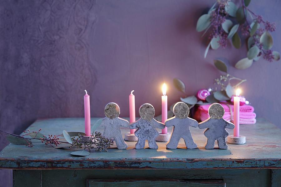 Lit Candles Behind Festive Paper Doll Chain Moulded From Concrete Photograph by Anke Schtz