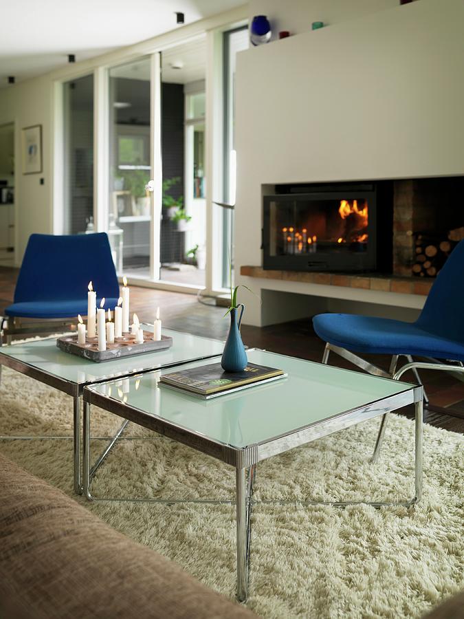 Lit Candles On Modern Coffee Table On Pale Flokati Rug In Front Of Fire In Open Fireplace Photograph by Peter Carlsson