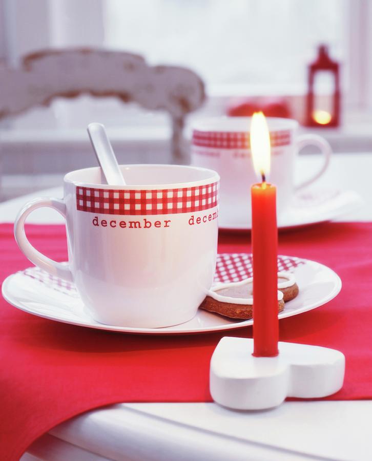 Lit, Red Candle In Heart-shaped Candle Holder And Teacups With Gingham Trim Photograph by Veronika Stark