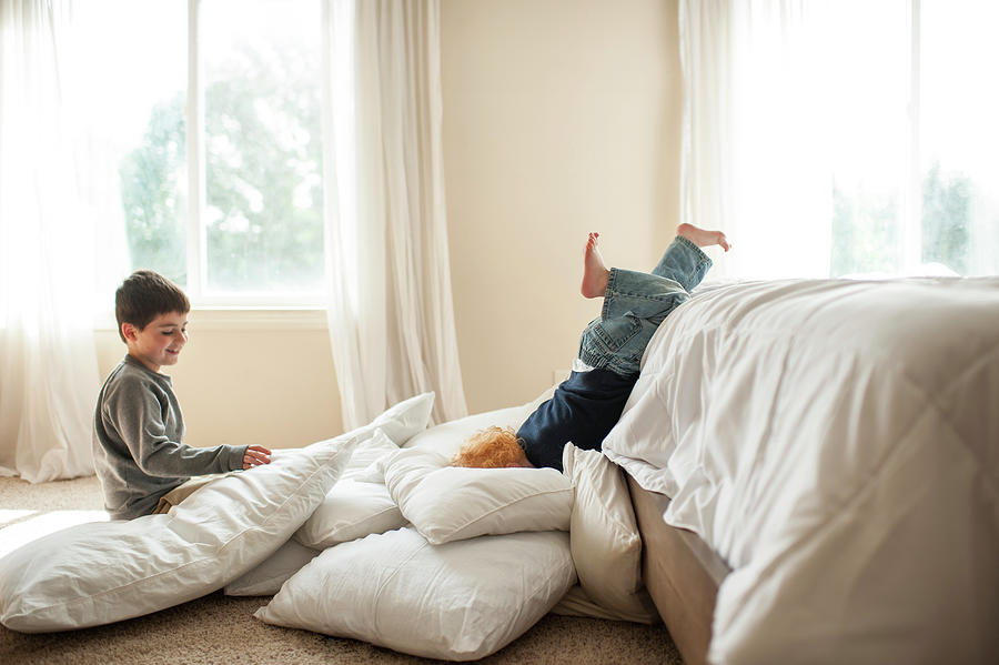 Little Brother Falling Off Bed Into Pillows In Bedroom At Home ...