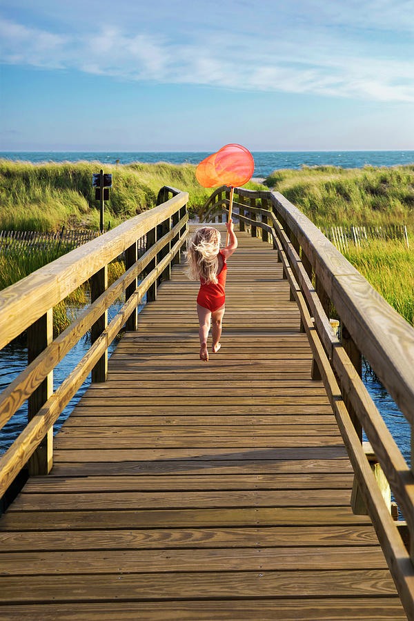 Little Girl From Behind Running On Bridge To Beach With Red