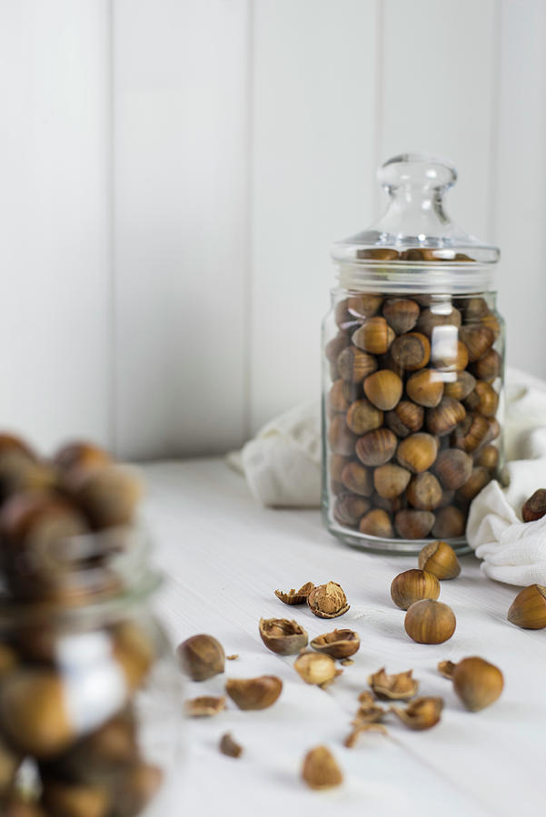 Loose Hazelnuts On A Table And In A Glass Storage Jar Photograph by Healthylauracom