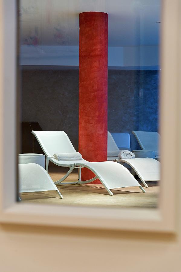 Lounges And Red Marbled Concrete Column In A Spas Relaxation Area Reflected In A Mirror Photograph by Anthony Lanneretonne