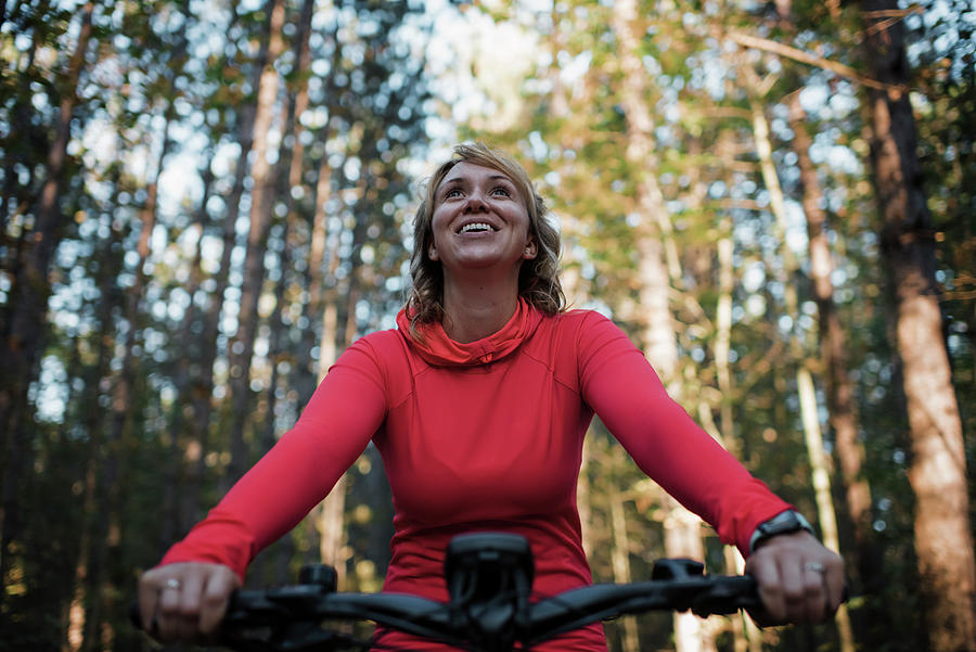 Tree Photograph - Low Angle View Of Cheerful Woman Mountain Biking Against Trees In Forest by Cavan Images