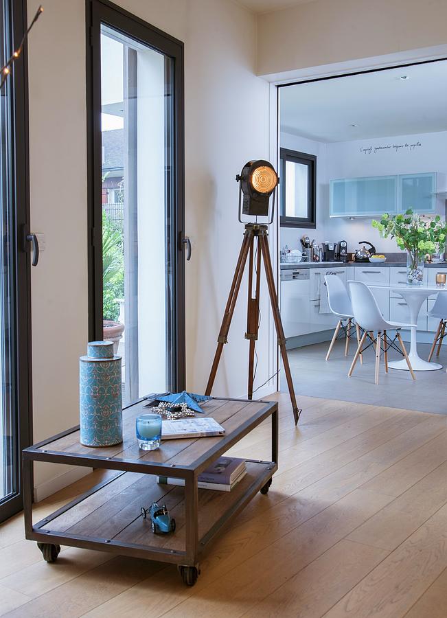 Low Sideboard On Castors, Industrial-style Tripod Lamp And View Into Kitchen-dining Room Photograph by Christophe Madamour