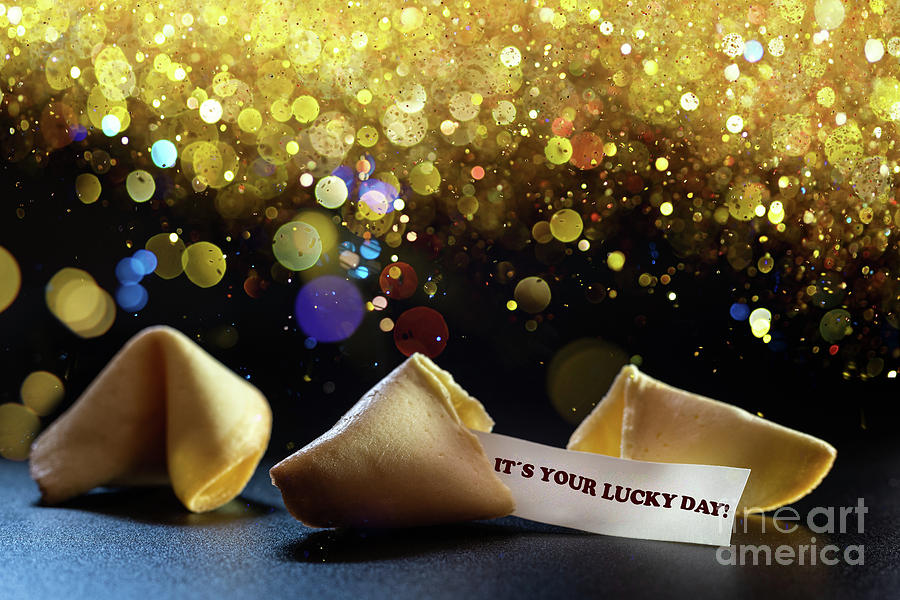 Lucky cookies broken with message of fortune, isolated on black background with empty space for text. Photograph by Joaquin Corbalan