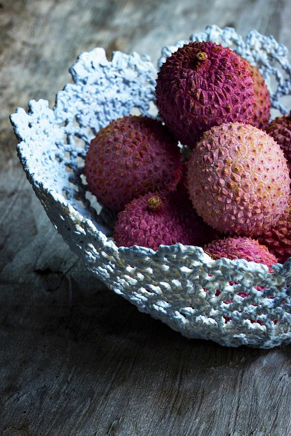 Lychees In A Grey Handmade Basket On A Wooden Surface Photograph by Charlotte Von Elm