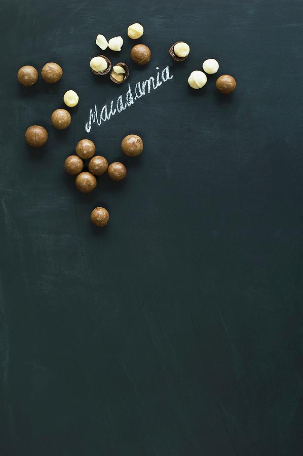 Macadamia Nuts, Whole And Hulled, Arranged Around The Word macadamia Written In Chalk On A Blackboard Photograph by Achim Sass