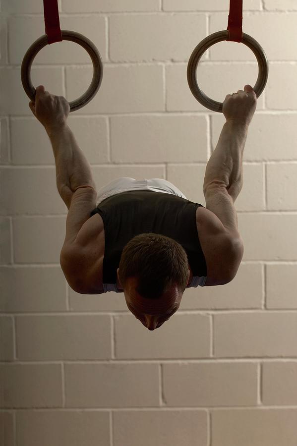 Male Gymnast Performing On Rings Photograph by Romilly Lockyer