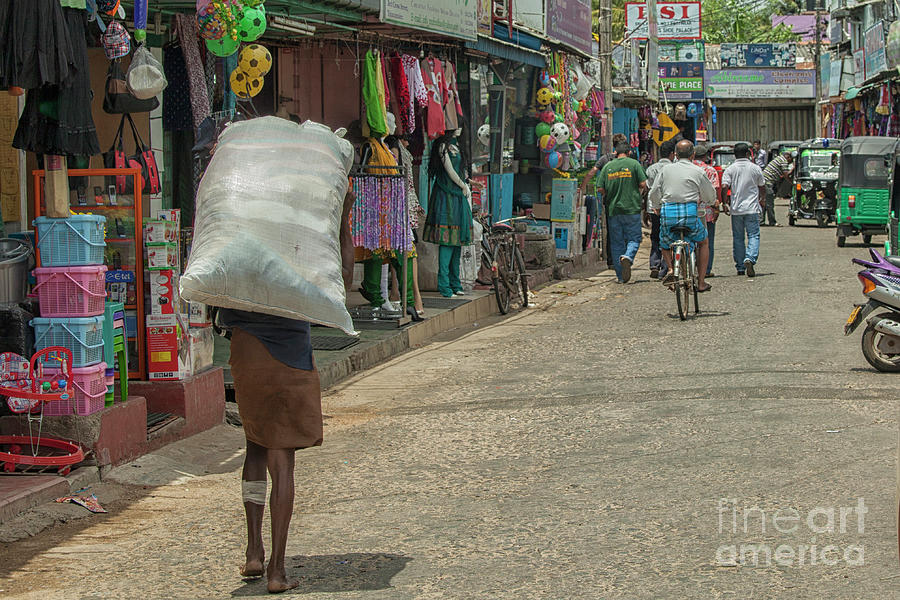 Man carrying heavy bag on the streets of Trincomalee in Sri Lanka Photograph by Patricia Hofmeester