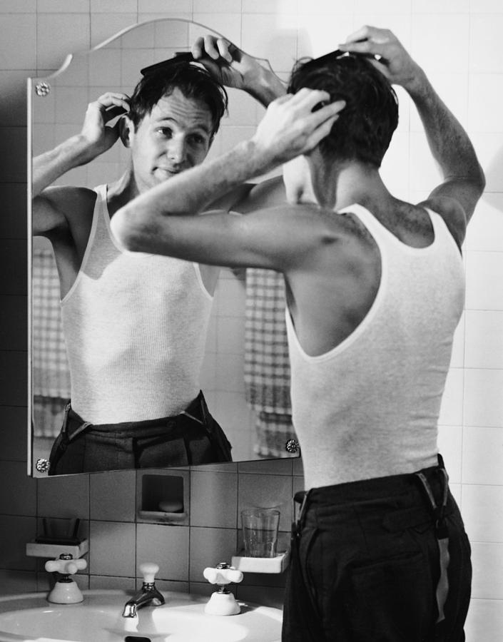 Man Combing Hair In Bathroom Photograph by George Marks