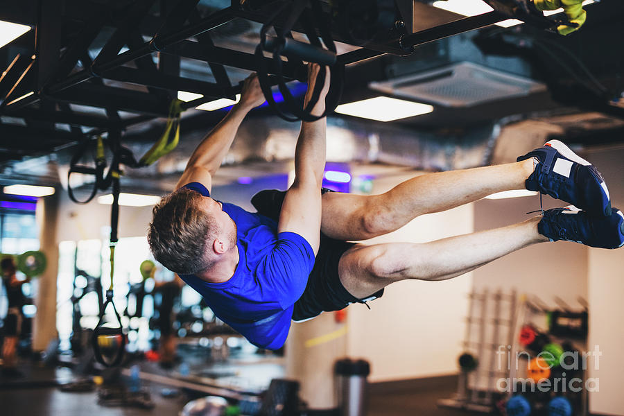 Man exercising on a rig at the gym. Photograph by Michal Bednarek