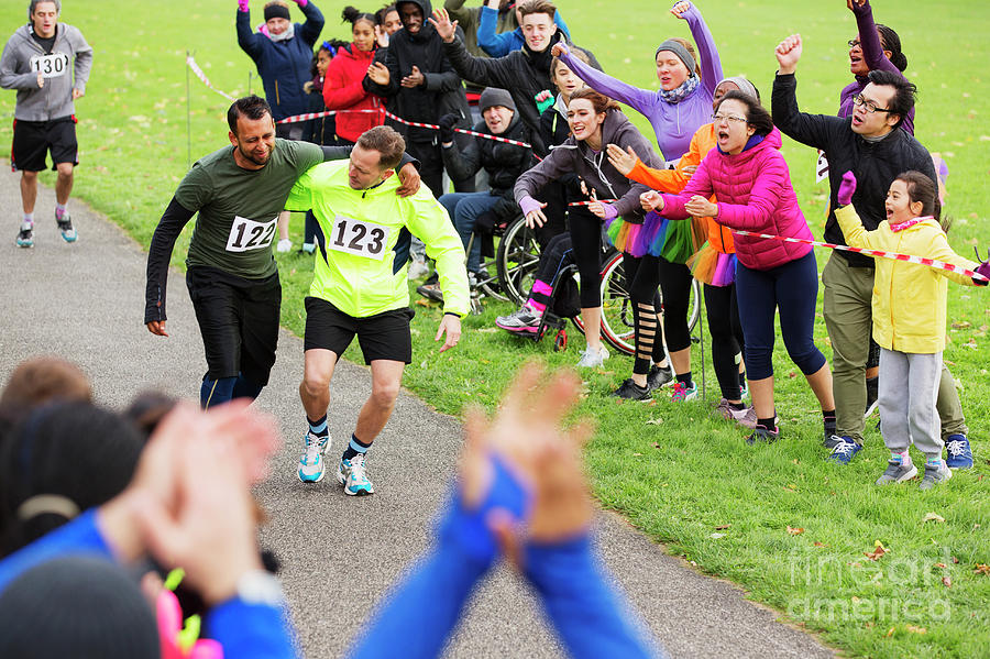 Man Helping Injured Runner Finish Charity Run Photograph by Caia Image ...