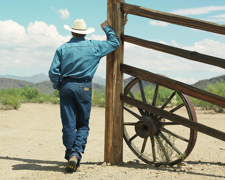 Man Leaning Against Ranch Fence Photograph by John Slater