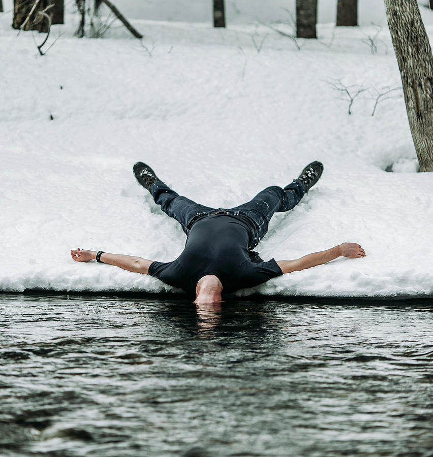 Man Lies On Back In Snow Spread Eagle With Head Underwater In River