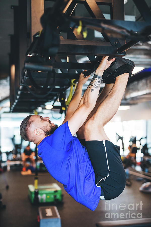 Sports Photograph - Man pulling his body up on the rig at the gym. by Michal Bednarek