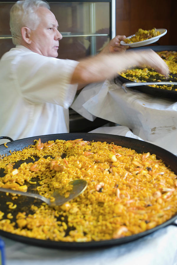Man Serving Paella, With Noodle Paella Photograph by Lonely Planet