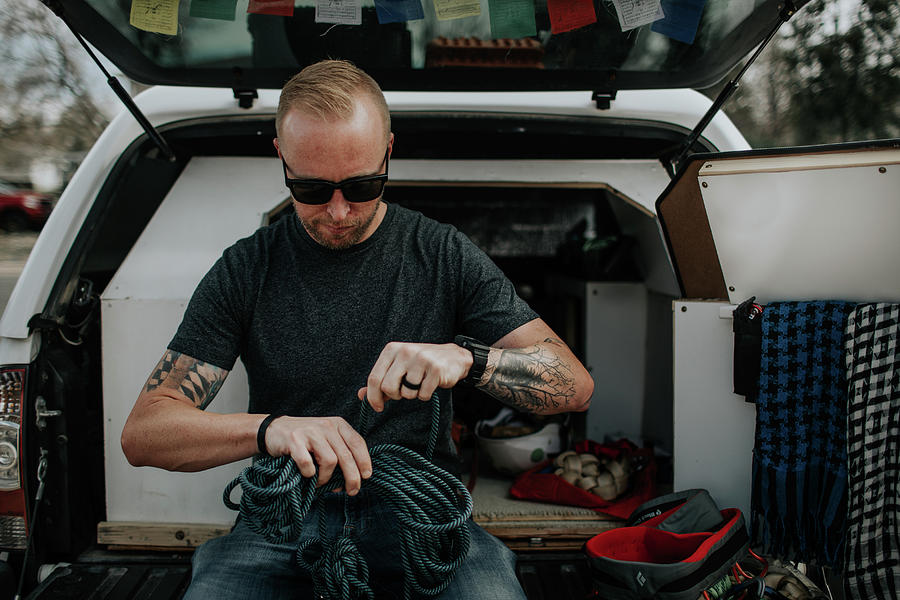 Man Sitting On Back Of Truck Preparing Rock Climbing Ropes Photograph ...