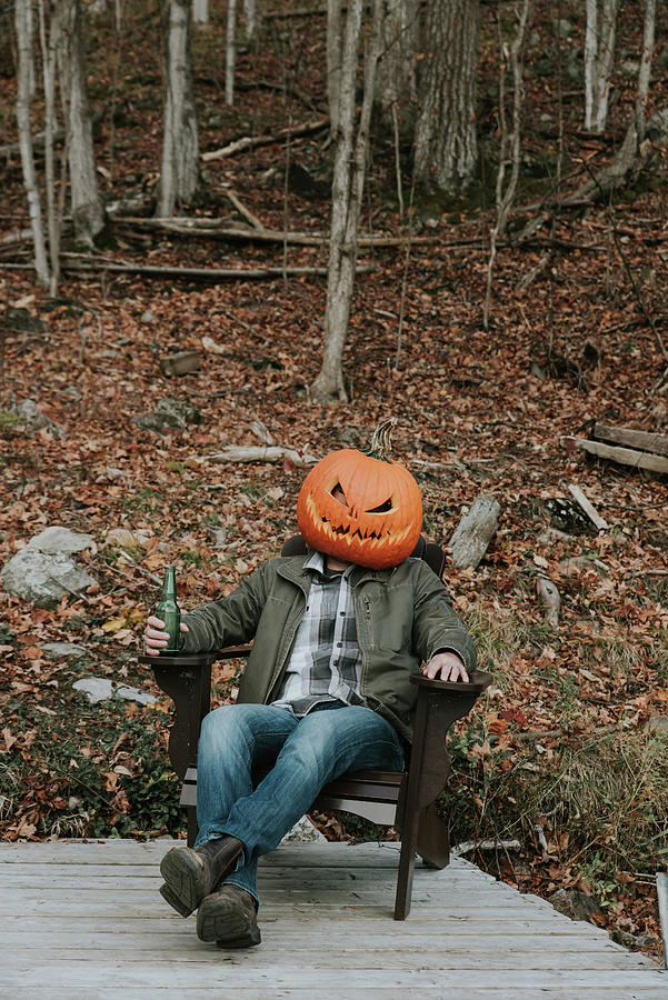 Pumpkin Photograph - Man Wearing Scary Pumpkin Head At Halloween Sitting On Dock With Beer. by Cavan Images