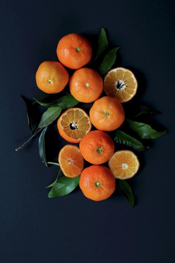 Mandarins And Mandarin Leaves On A Blue Surface Photograph by Sylvia E.k Photography