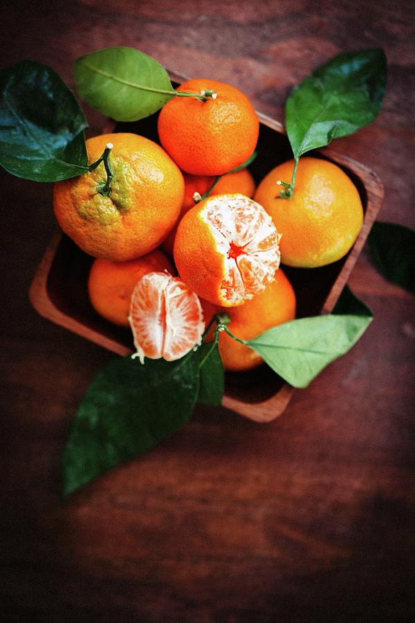 Mandarins With Leaves On A Rustic Wooden Surface Photograph by Alena Haurylik