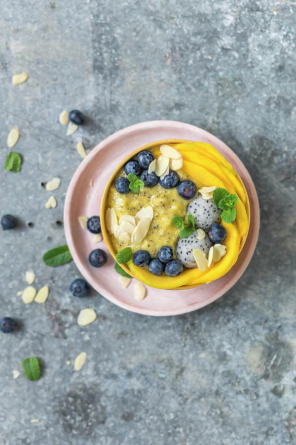 Mango And Chia Smoothi Bowl Decorated With Mango Slices, Blueberry, Pitaya And Almond Flakes Photograph by Malgorzata Laniak