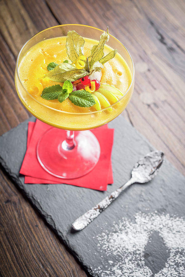 Mango Sorbet Decorated With Citrus Peel, Mint, Redcurrant In A Glass With A Red Napkin And A Spoon On A Slate Board And Wooden Background Photograph by Giulia Verdinelli Photography