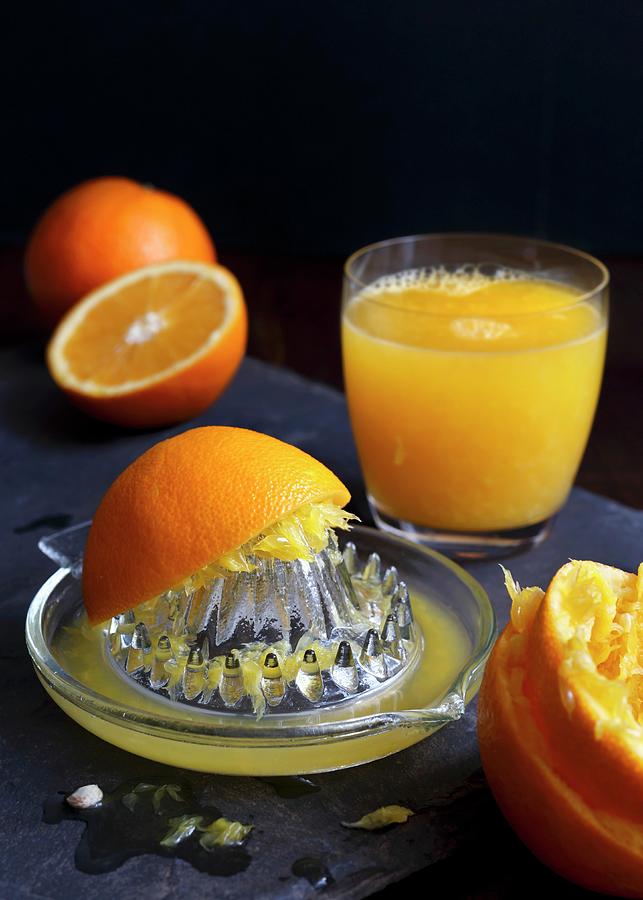 Manual Glass Juicet Extractor With Squeezed Oranges And A Glass Of Orange Juice On A Dark Slate Photograph by Etienne Voss