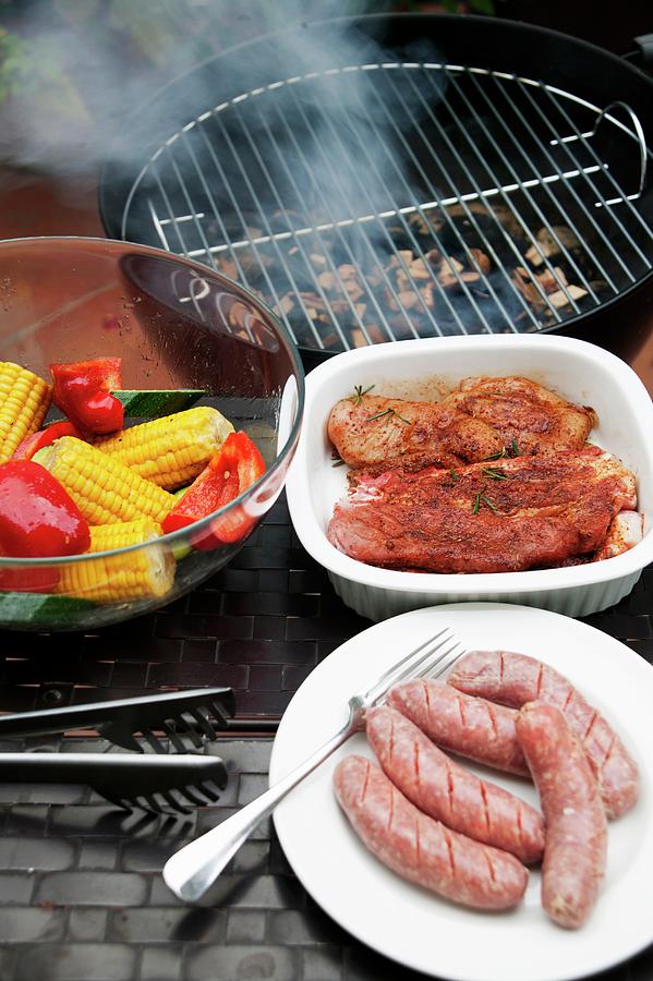 Marinated Pork Steaks, Sausages And Vegetables In Front Of A Hot Barbecue Photograph by Food Experts Group