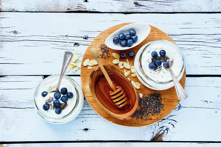 Mason Jars Of Breakfast Yogurt With Chia Seeds, Honey And Fresh Blueberries On White Grunge Wooden Background Photograph by Yuliya Gontar
