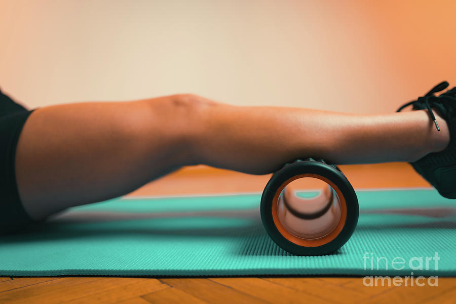 Massaging Calf Muscles With Foam Roller Photograph by Microgen Images