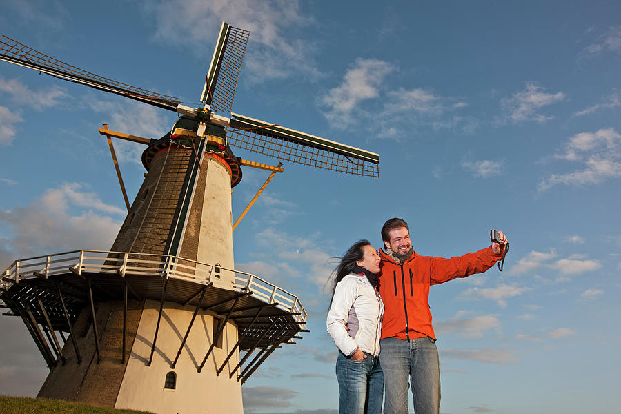Architecture Photograph - Mature Couple Taking Selfie With Windmill In The Netherlands by Cavan Images