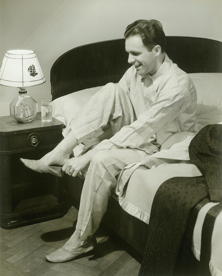 Mature Man Sitting On Bed Putting On Photograph by George Marks