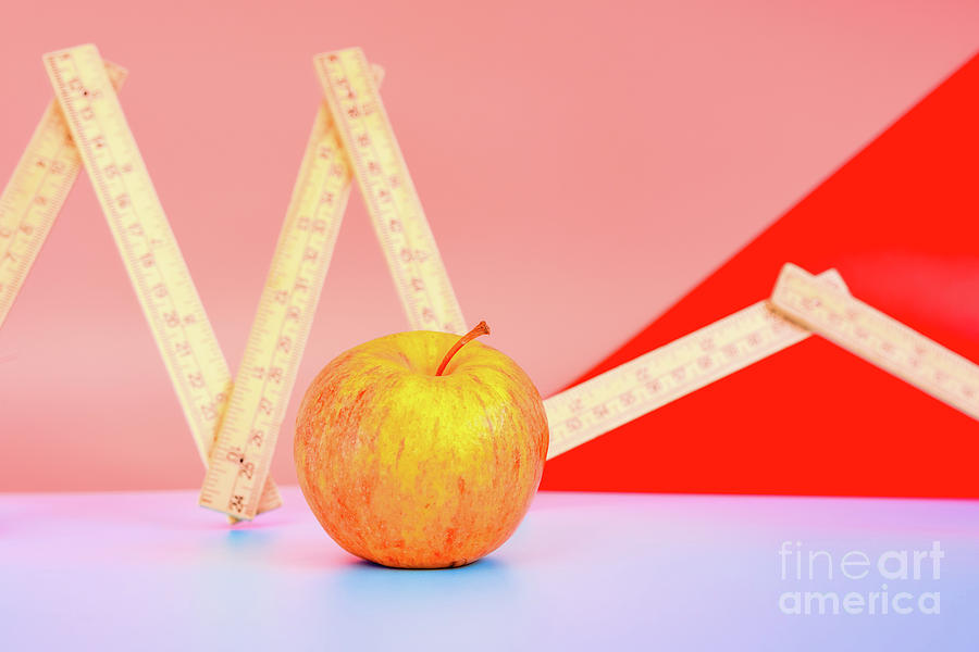 Measuring tape next to an apple, concept of weight loss with healthy diet. Photograph by Joaquin Corbalan