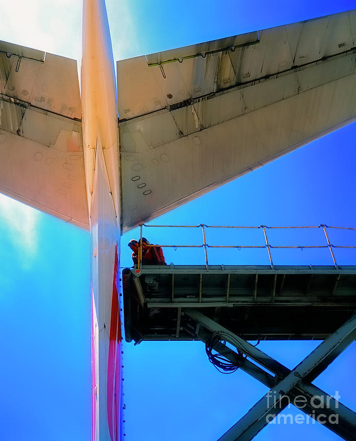 Mechanics working on the tail of a commercial airliner  Photograph by Tom Jelen