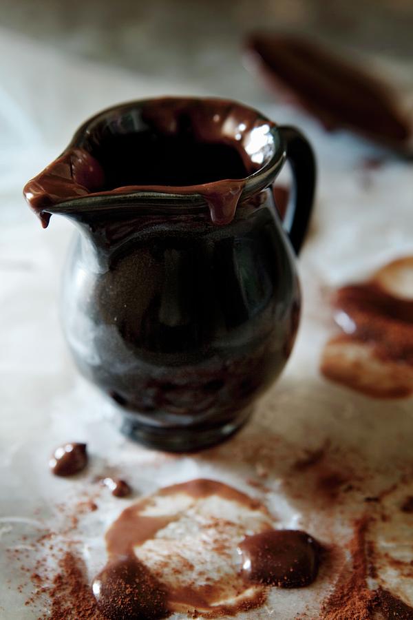 Melted Chocolate In And On A Dark Ceramic Jug Photograph by Ulrika Ekblom