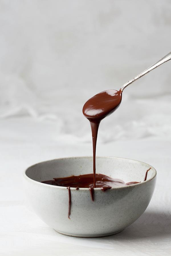 Melted Dark Organic Chocolate Dripping From A Spoon Into A Bowl Photograph by Rose Hewartson