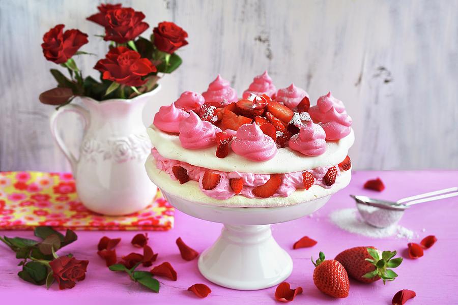 Meringue Cake With Cream, Strawberries And Rose Petals On A Cake Stand In Front Of A Vase Of Red Roses Photograph by Mariola Streim