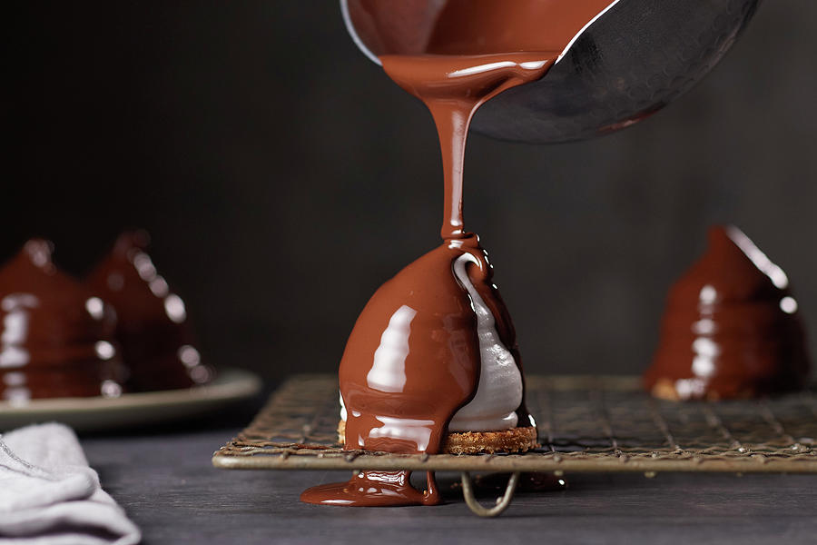 Meringues Being Coated With Chocolate Photograph by Nikolai Buroh