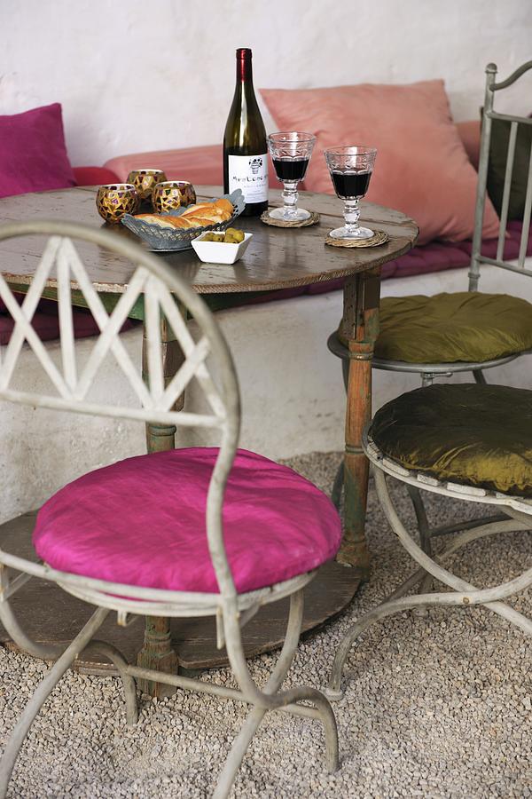 Metal Bistro Chairs With Round Seat Cushions At Antique Wooden Table Set With Bread And Wine Photograph by Twins