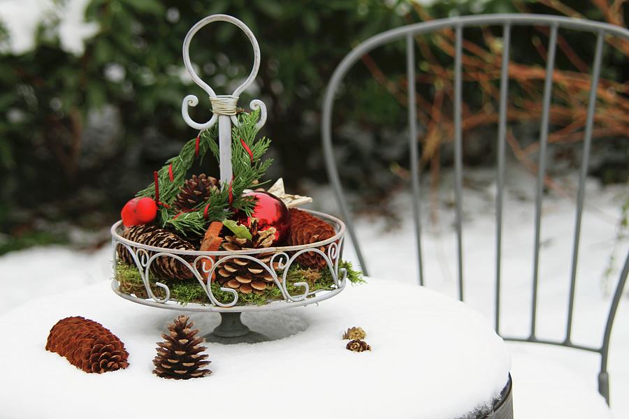 Metal Cake Stand With Natural Decorations And Baubles On Snowy Garden Table Photograph by Barbara Ellger