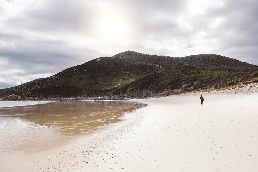 Mountain Photograph - Mid Distance View Of Hiker Walking At Beach Towards Mountains Against Cloudy Sky by Cavan Images