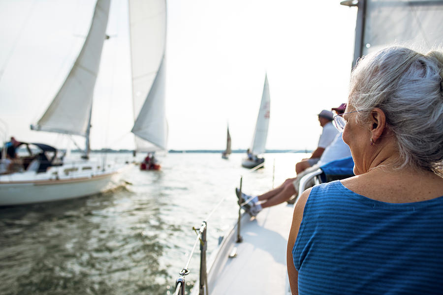 Nature Photograph - Middle Aged Woman Enjoying Summer Sail Race During Golden Hour by Cavan Images
