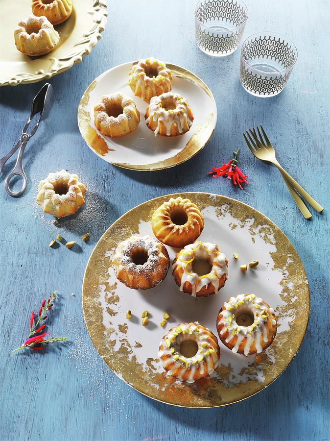 Mini Bundt Cakes On Gold-patterned Plates On A Blue Wooden Surface Photograph by Christian Schuster
