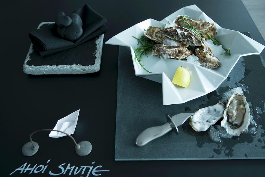Minimalist Table Arrangement In Charcoal - Iced Oysters In Crumpled-effect Dish On Table Top Painted With Blackboard Paint Photograph by Matteo Manduzio