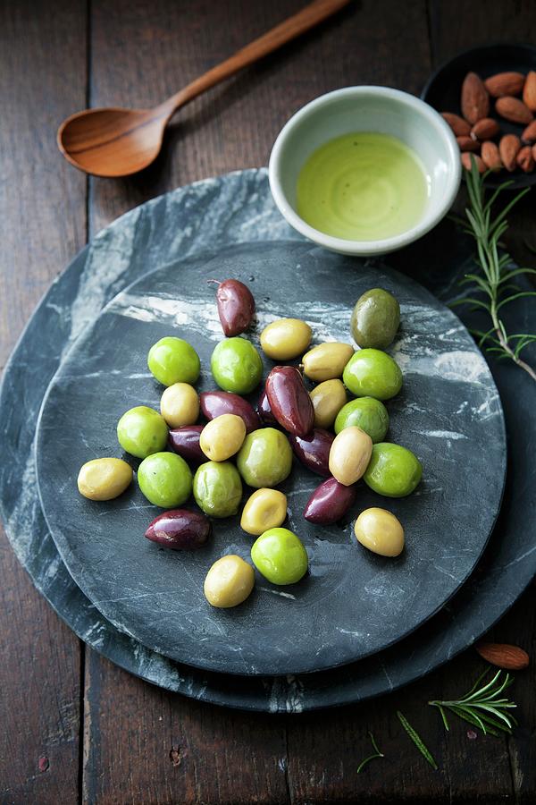 Mixed Black And Green Olives With Almonds, Olive Oil And Rosemary Sprigs Photograph by Victoria Firmston